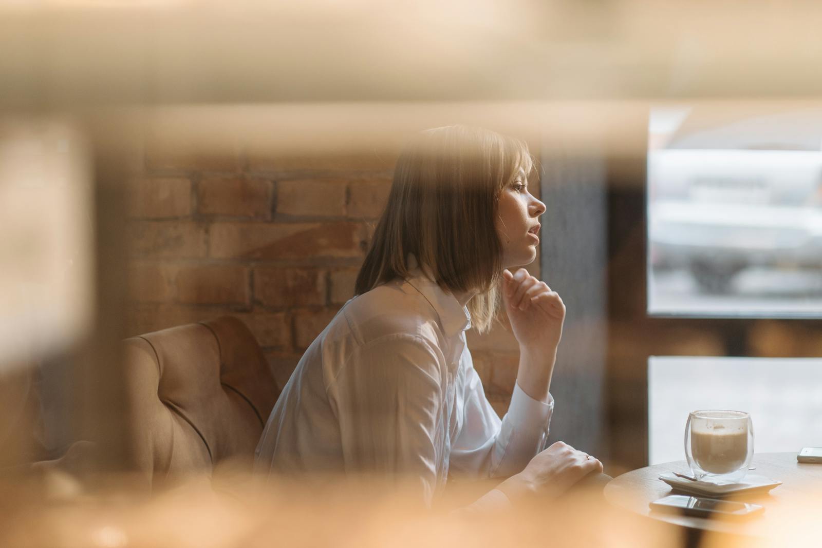 A woman alone at a cafe, gazing out the window over a latte